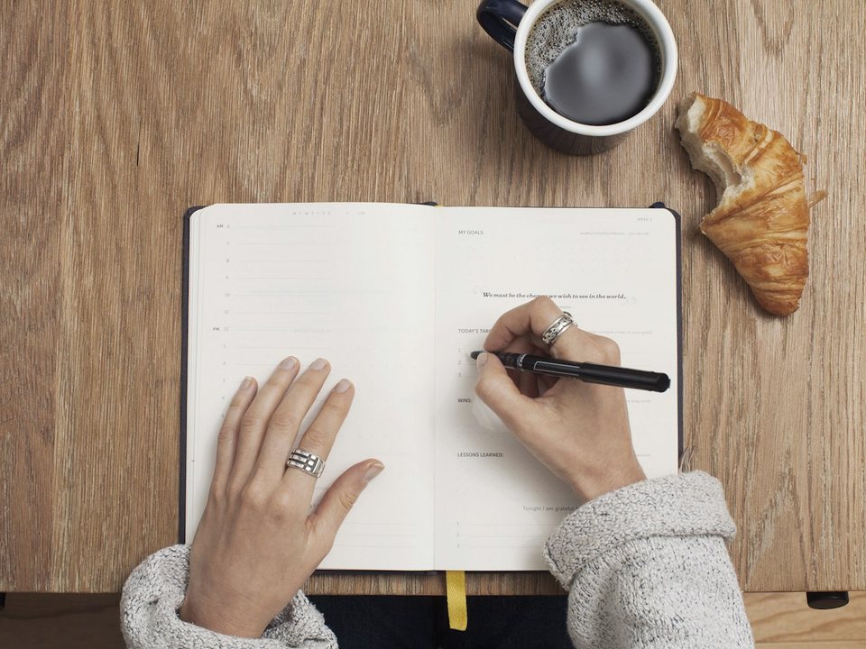 Hand writing a day-by-day travel itinerary in a planner