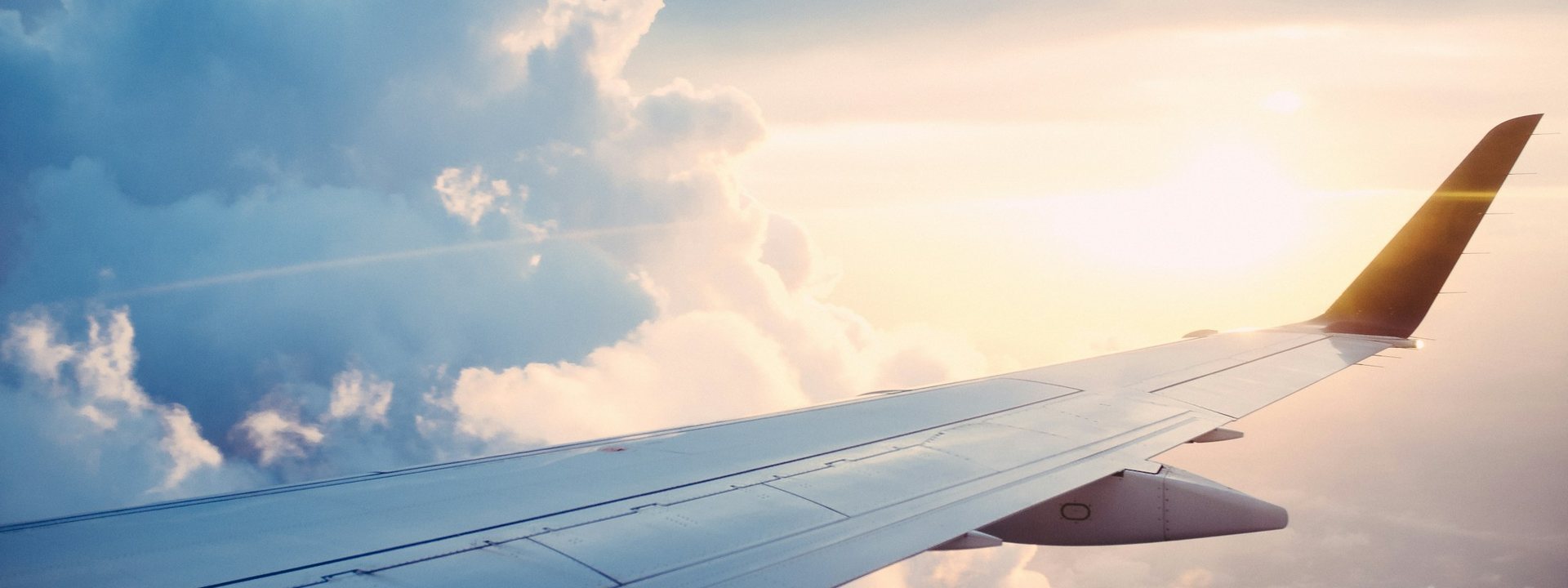 Airplane wing above the clouds at sunset on the way to a trip