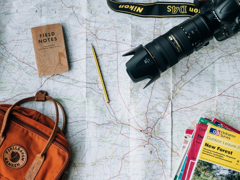 Map, camera and backpack laid out while organising a trip